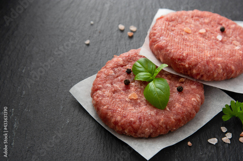 Raw red meat cotlets, cooking burgers. Minced red meat on black board. Copy space