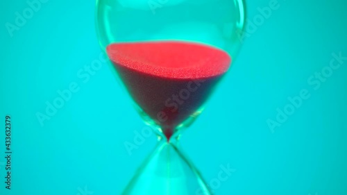Sand flowing through the hourglass, measuring the elapsed time in the countdown to the deadline on a blue background.