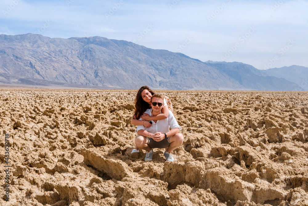 A beautiful young tourist couple a man and a woman embrace on the Devil's Golf course in Death Valley