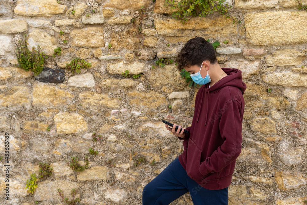 Fototapeta premium boy with mask using mobile phone