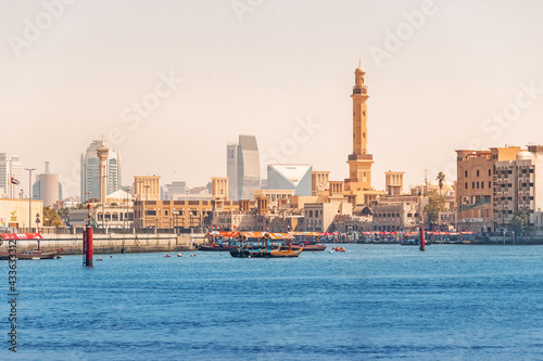 Scenic view of Dubai Creek district with skyscrapers, Arba dhow ferry boats and Al Farooq mosque minaret. Famous old district of the city attracts numerous tourists and authentic travelers photo