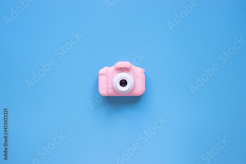 Small pink toy camera on a blue background. Minimalism.