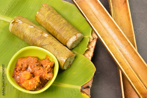 Malaysian traditional food called as LEMANG and chicken rendang on banana leaves. Glutinous rice is wrapped with lerek or banana leaf encased in bamboo culm and cooked in open fire photo