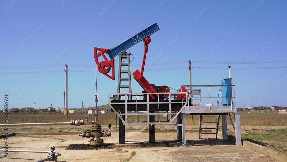 pumping station for oil production in a green field against a blue sky pumping station for oil production in a green field against a blue sky
