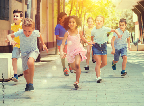 Group of joyful children running down the summer city street