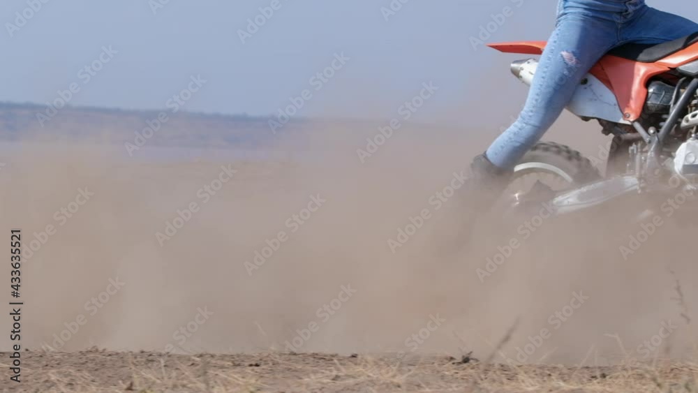 Man rides red bike in sand countryside area near lake creating large dust cloud and falls down at sunlight super slow motion