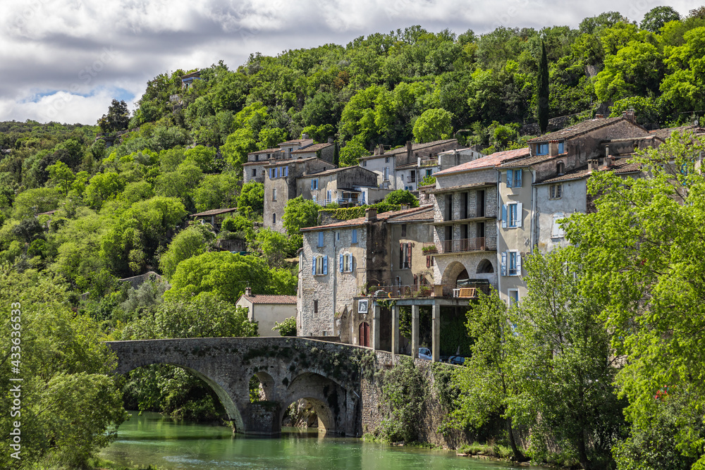 Vue sur les vieilles maisons et la forêt du village médiéval de Sauve depuis les bords du Vidourle (Occitanie, France)