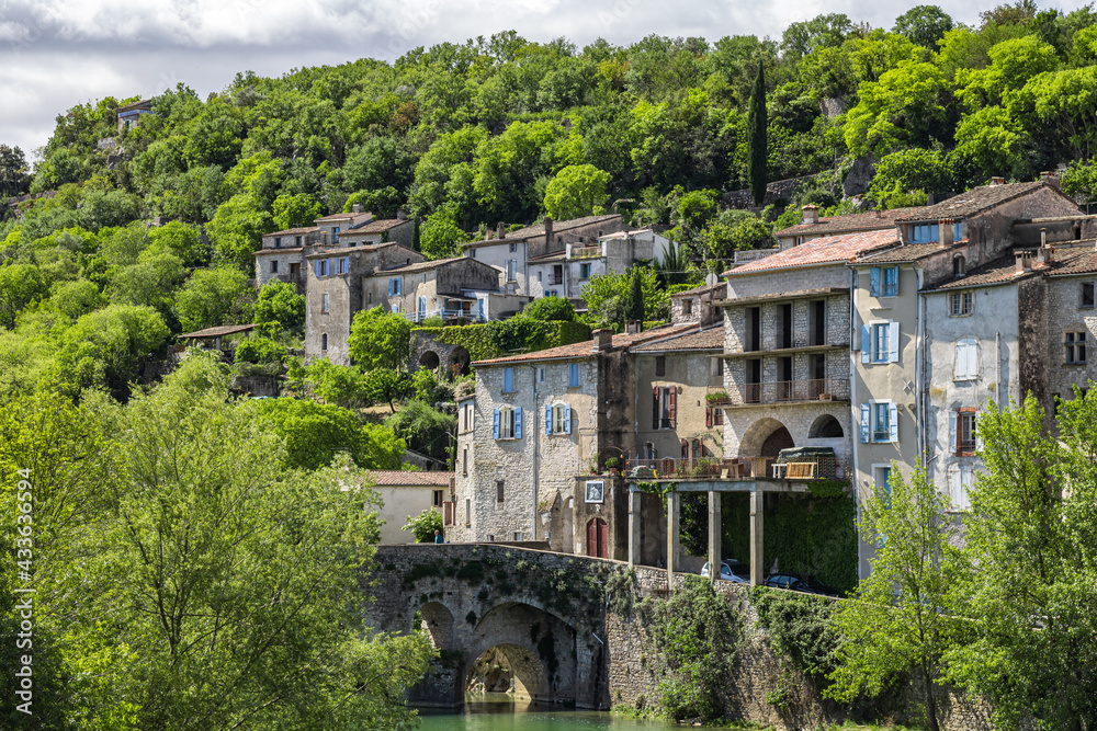 Vue sur les vieilles maisons et la forêt du village médiéval de Sauve depuis les bords du Vidourle (Occitanie, France)