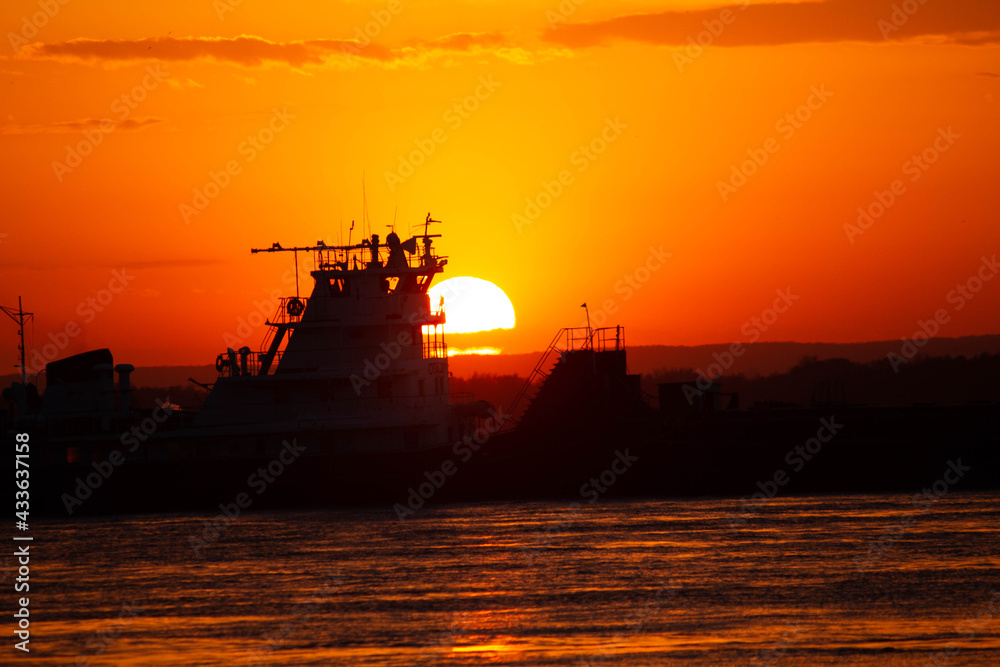 Ship on sunset, bright orange sun, big river