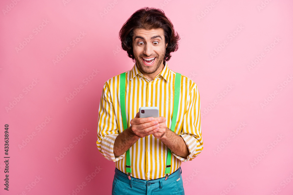 Photo of young handsome shocked happy amazed cheerful man using smartphone isolated on pink color background Photo of young handsome shocked happy amazed cheerful man using smartphone isolated on pink color background