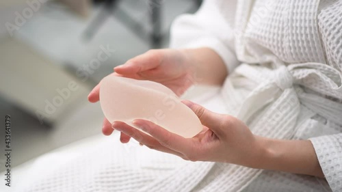 Hand of young woman patient preparing for breast augmentation with silicone breast augmentation is testing silicone breast augmentation in a beauty clinic.