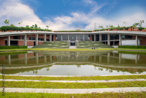 view of the park in Thammasat University There are ponds and courtyards with beautiful green lawns and trees. A cement sculpture of two people sitting on a vintage chair, outdoor building photo