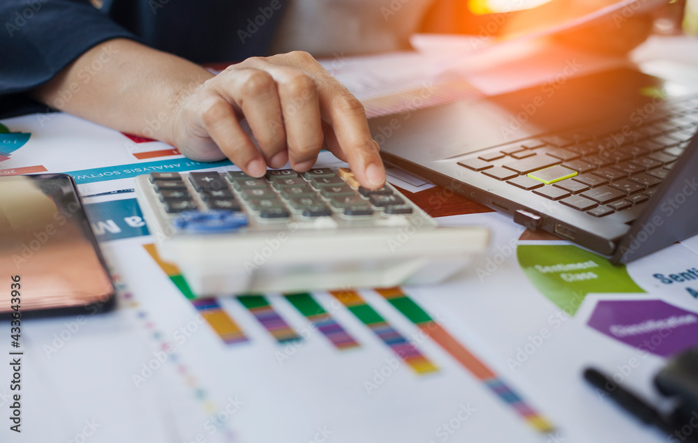 Close-up of businessmen or accountants holding a pen and pressing on the calculator to calculate business information, Finance documents, business ideas. Close-up of businessmen or accountants holding a pen and pressing on the calculator to calculate business information, Finance documents, business ideas.