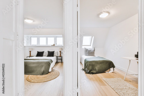 фотографія Comfortable beds located behind opened doors of separate light bedrooms in light