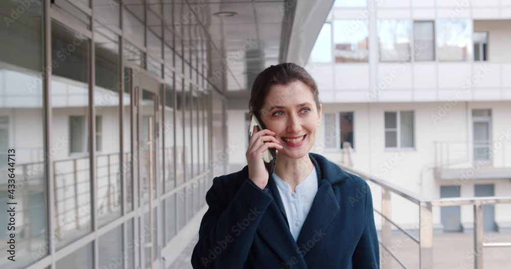 Happy confident businesswoman talking on phone while walking outdoors. Happy confident businesswoman talking on phone while walking outdoors.