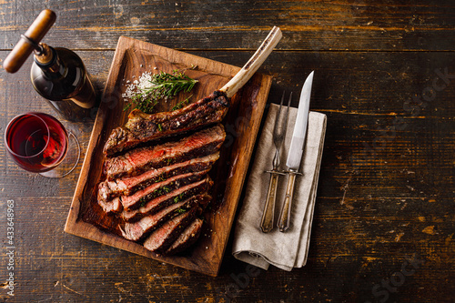 Grilled sliced Tomahawk Steak and glass of wine photo