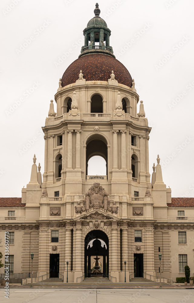 Pasadena, CA, USA - May 11, 2021: Closeup of Beige stone, look-through, sculpted tower with red tiled dome and greenish top of historic City Hall under silver sky. 