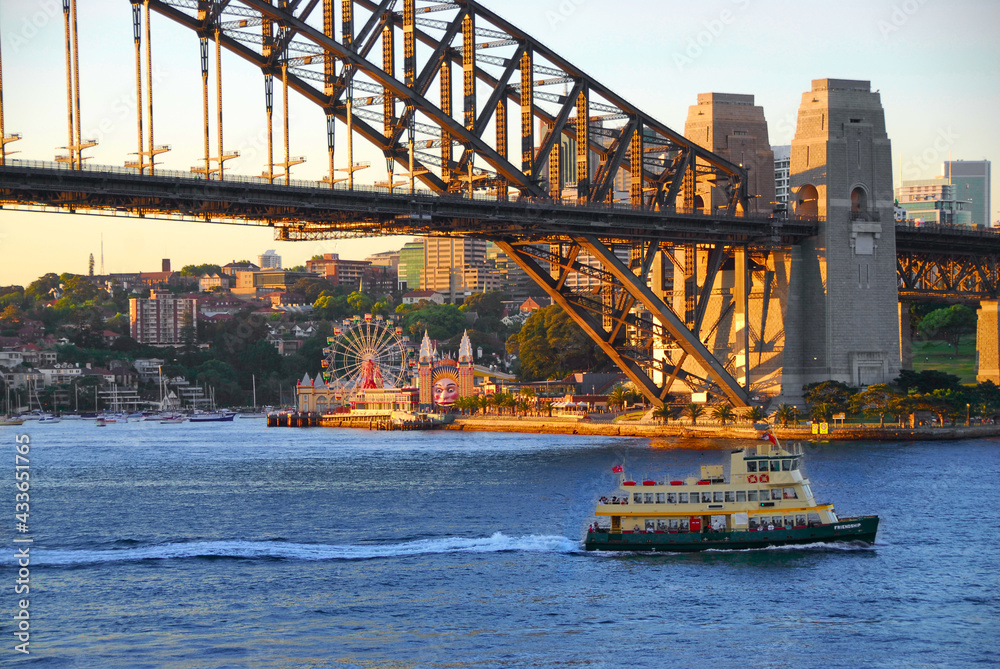 Obraz premium A Sydney Harbour ferry cruising past the Harbour bridge on a early evening run in Sydney, Australia.