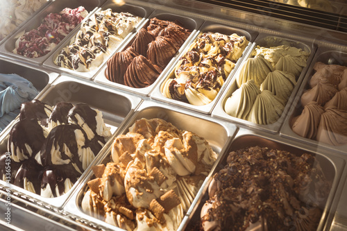 Selection of two rows of ice cream of different flavours in stainless steel containers