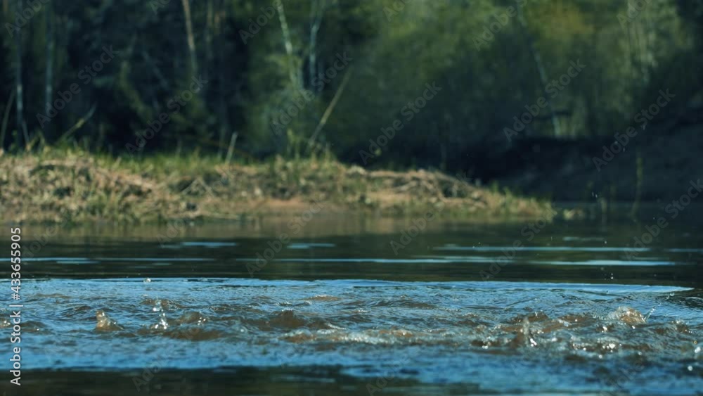 Child runs barefoot on the river bank. Water splashes in all directions Child runs barefoot on the river bank. Water splashes in all directions