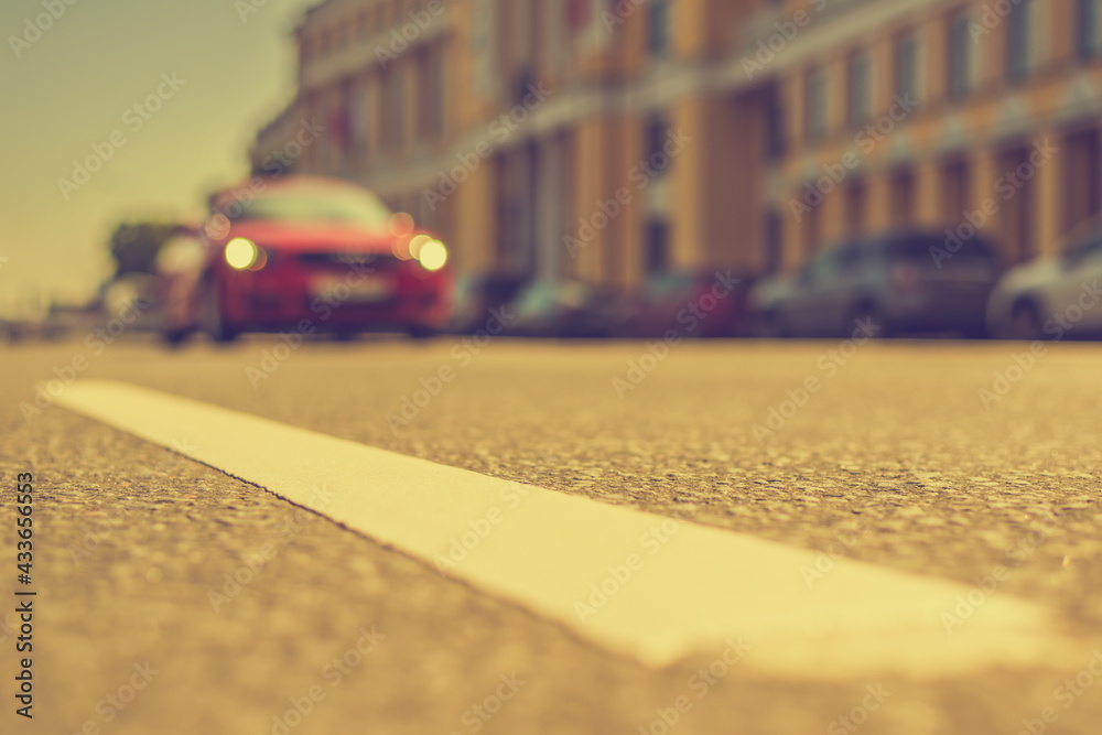 Road near luxury mansion, the red car racing down the street. Close up view from the level of the dividing line