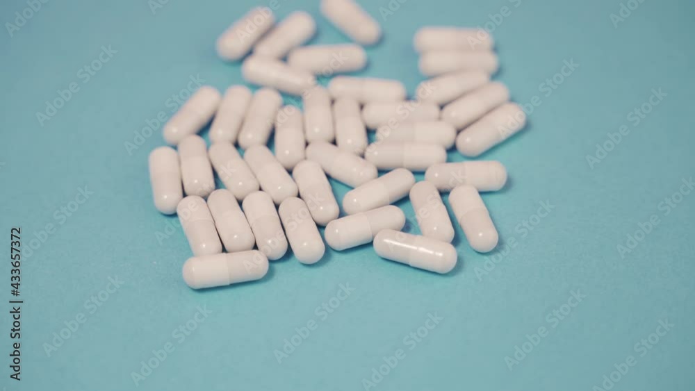a lot of white pills on a blue background spin counterclockwise a lot of white pills on a blue background spin counterclockwise