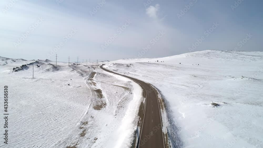 Aerial view on a road between the white snowy hills against the blue sky. Aerial view on a road between the white snowy hills against the blue sky.
