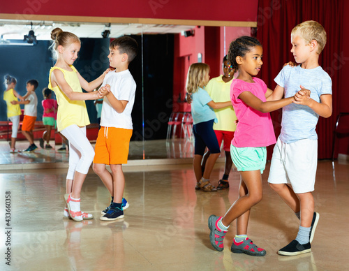 Group of happy cheerful smiling childrens trying dancing with partner in classroom