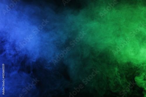 Magic smoke in blue green light on black background