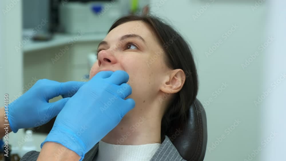Portrait of woman in dentistry, doctor orthodontist removes silicone teeth trainer from her mouth. Correcting teeth, hands in gloves closeup. Correction of the bite and treatment of the jaw joint. Portrait of woman in dentistry, doctor orthodontist removes silicone teeth trainer from her mouth. Correcting teeth, hands in gloves closeup. Correction of the bite and treatment of the jaw joint.