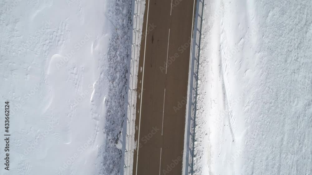 Aerial top down view on a road between the white snowy fields. Beautiful winer landscape