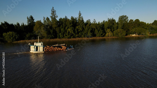 Aerial side view of boat with wood in Amazon River during sunset