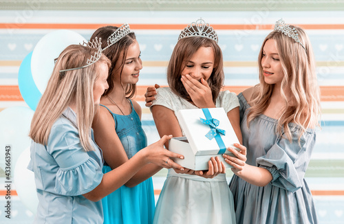 Nice friends giving present to happy birthday girl