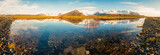 Icelandic mountain range with beautiful snowcapped mountains reflected into still water. Majestic panoramic view.