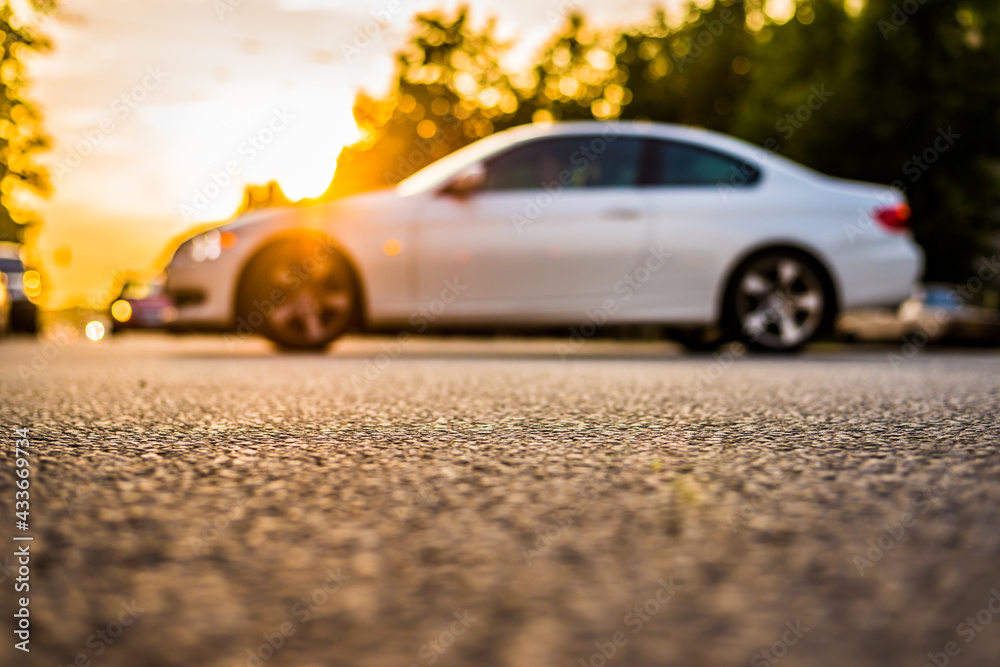 Fototapeta premium Sunset in the suburbs, the car drives off the highway. Close up view from the asphalt level