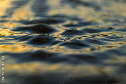 Soft sunlight, golden hour. Sea shore at sunset, close-up. storm waves. Abstract background, details blurred in bokeh. Blue, yellow, orange colors. Peace, meditation, tranquility themes
