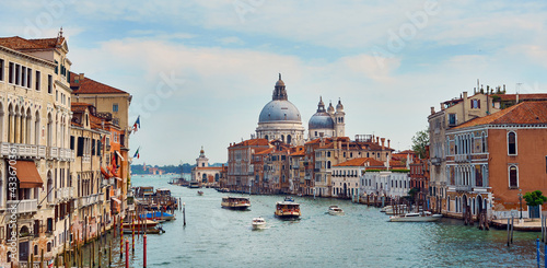 Famous Grand Canal with floating boats between residential buildings under blue sky in Venice photo