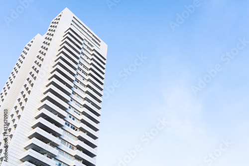 Low angle view of a modern white skyscraper in perspective with blue sky and copy space. Architecture background concept