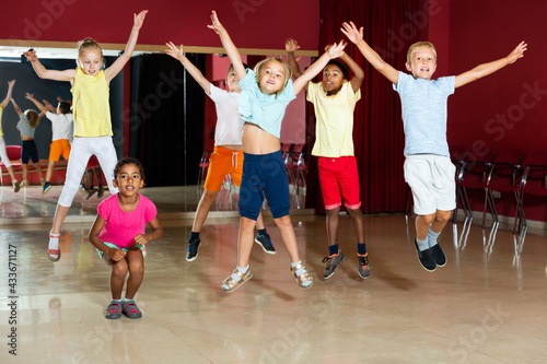 Cheerful little boys and beautiful girls jumping and having dancing class in studio