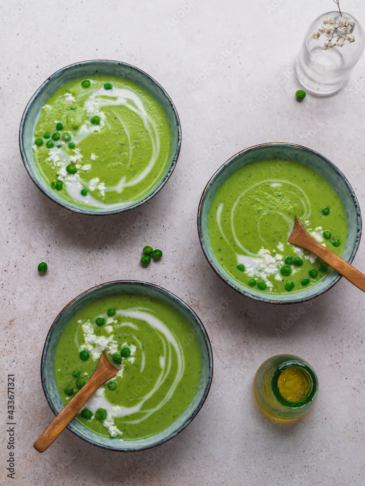 Top view of delicious pea cream soup in bowls served on table with vase with flowers Top view of delicious pea cream soup in bowls served on table with vase with flowers