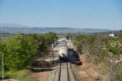 Long straight train tracks in an Andalusian agricultural landscape on a sunny day