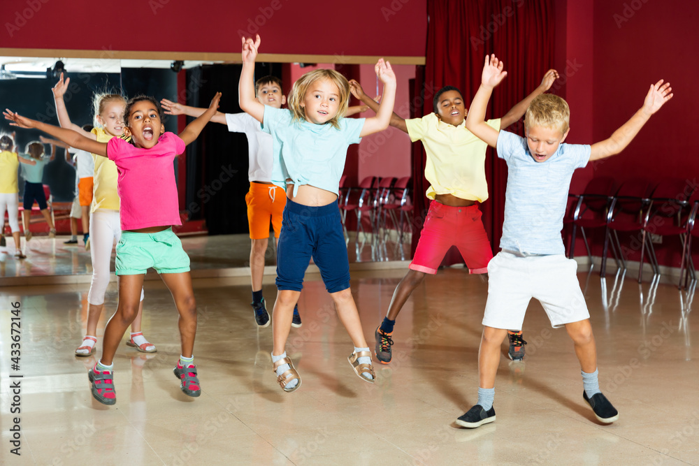 Cheerful little boys and beautiful girls jumping and having dancing class at studio