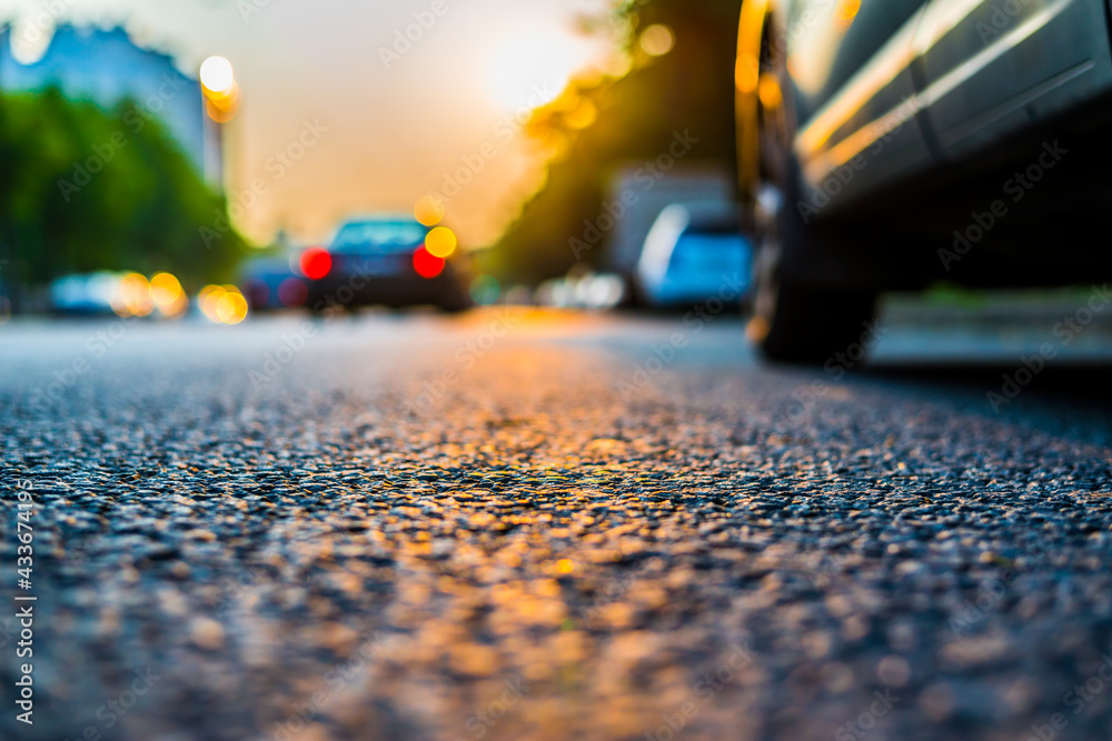 Sunset in the city, the headlights of the approaching cars. Close up view from the asphalt level Sunset in the city, the headlights of the approaching cars. Close up view from the asphalt level