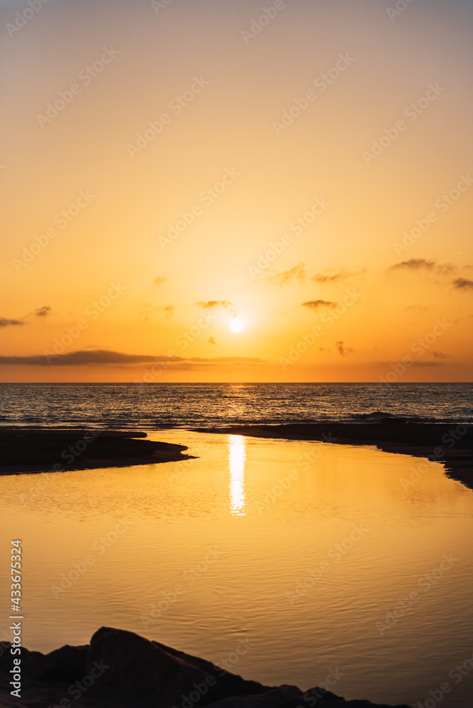 Scenic view of vivid orange sunset sky over calm sea water in evening Scenic view of vivid orange sunset sky over calm sea water in evening