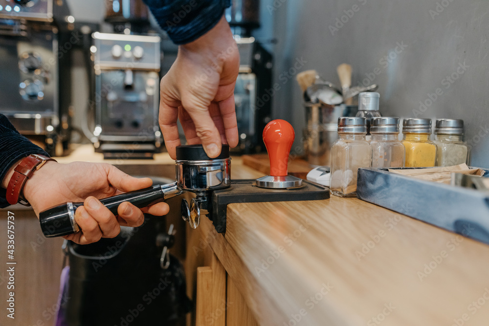 Crop faceless barista standing at table and preparing fresh aromatic coffee while working in cafeteria in daytime Crop faceless barista standing at table and preparing fresh aromatic coffee while working in cafeteria in daytime