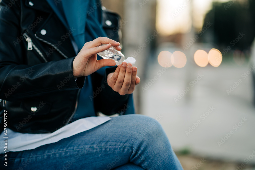 Crop unrecognizable Muslim female in hijab applying antibacterial sanitizer on hands in city street during coronavirus pandemic Crop unrecognizable Muslim female in hijab applying antibacterial sanitizer on hands in city street during coronavirus pandemic