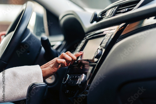 Crop anonymous female touching screen of multimedia control panel in luxury automobile in daytime