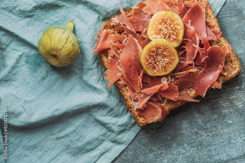 Delicious toast of Iberico ham, cheese and fresh figs on the blue tablecloth, Delicious appetizer, ideal as an aperitif. Healthy food photo