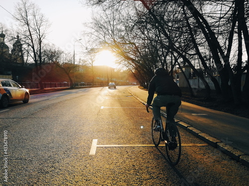 cyclist rides through the city at sunset © Igor Rafa