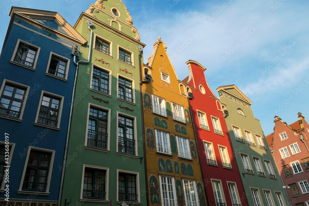 Fototapeta premium A close up of the facades of tall building in the middle of Old Town in Gdansk, Poland. The buildings have many bright colors, they are richly decorated. City tour. Clear day.